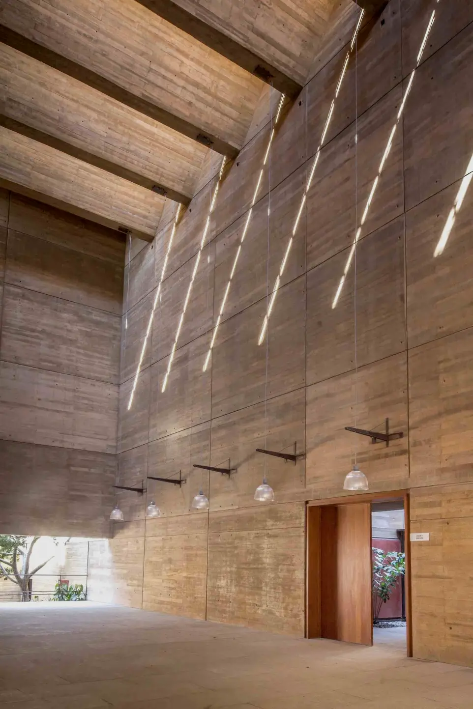 Interior architectural space with exposed concrete surfaces and suspended linear lightingAho